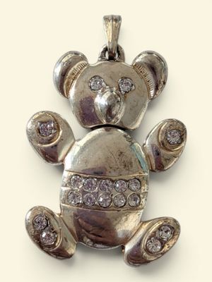 a small silver teddy bear with diamonds on it ' s back