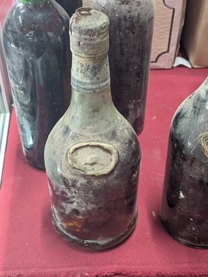 several old bottles are sitting on a red cloth on a table