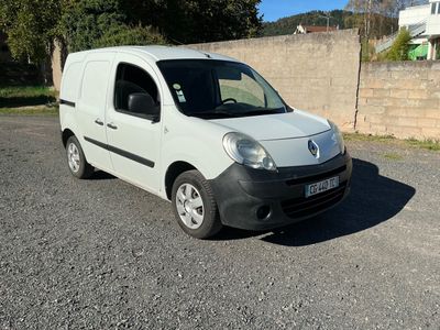 une camionnette blanche garée sur un parking près d'un mur de briques