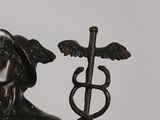 statue of a man holding a staff with a snake on it ' s head