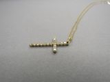 un collier avec une croix en or sertie de diamants sur un fond gris