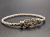 a close up of a silver bracelet with a knot on it