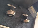 a pair of silver cufflinks and a pair of silver cufflinks on a black cloth