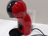 une cafetière rouge et noire posée sur une table blanche
