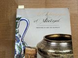 Le livre est posé sur une table, à côté d'un vase et d'autres objets.