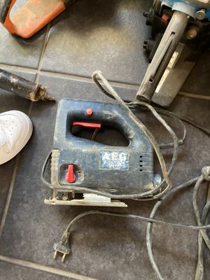 une petite ponceuse filaire posée par terre à côté d'une paire de chaussures