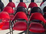 Des rangées de chaises rouges et noires sont disposées dans une pièce dotée d'une grande fenêtre
