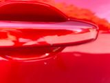 the reflection of a red car is seen in the rear view mirror