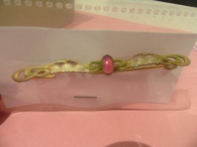 someone is holding a card with a picture of a pink bead on it