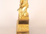 gold statue of a woman sitting on top of a wooden table