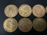 six different british coins sitting on top of a black surface