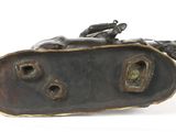 bronze sculpture of a horse laying down on its back on a white surface