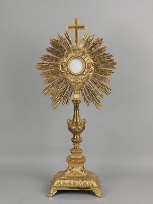 une assiette en or ornée d'une croix, surmontée d'une autre croix