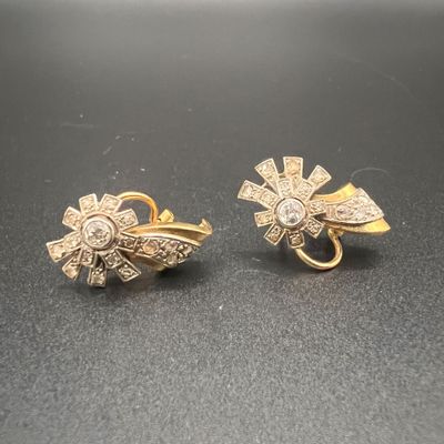 deux paires de boucles d'oreilles en or et diamants posées sur un fond noir