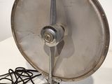 a metal fan sitting on a table with a cord attached to it