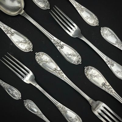 de nombreuses cuillères et fourchettes en argent posées sur une table noire