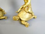 deux figurines en or posées sur le dos d'une tortue