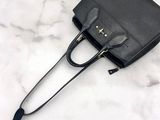 a black handbag on a marble surface with a black handle