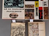 trois livres exposés sur une surface grise, avec des photos de bâtiments et de personnes