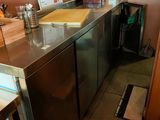 une petite cuisine équipée d'un plan de travail en inox et d'un réfrigérateur