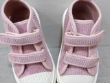 pink baby shoes with white soles on a grey surface