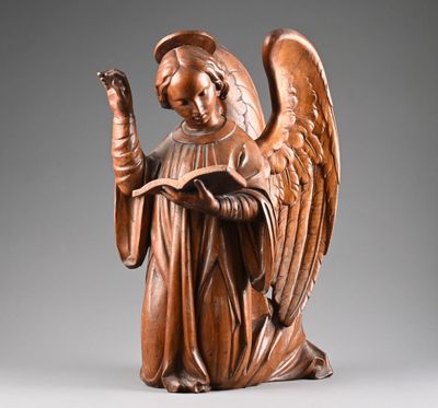 une statue ancienne en bois représentant un ange tenant un livre