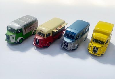 quatre camions miniatures posés côte à côte sur une surface blanche