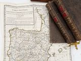 two old books and a map on a white surface