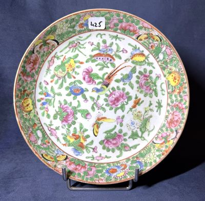une assiette ornée de fleurs et d'oiseaux, posée sur un socle