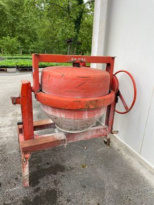 une bétonnière rouge posée sur un socle à l'extérieur