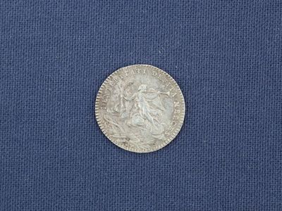 un gros plan d'une pièce d'argent posée sur un tissu bleu