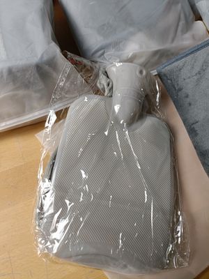 une bouillotte dans un sac en plastique posée par terre