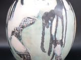 a white vase with a painting on it sitting on a table