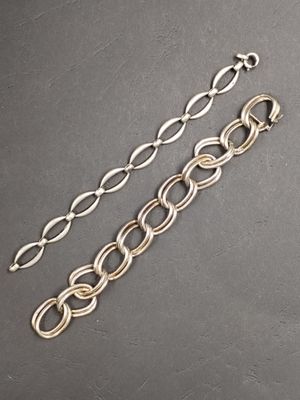 un gros plan sur deux bracelets à chaîne argentée posés sur une table