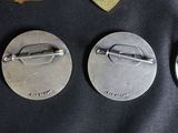 three metal buttons with a pin on them sitting on top of a table