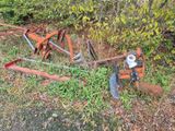 une charrue rouillée posée par terre à côté d'un buisson