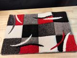 un tapis posé au sol, orné d'un motif rouge, noir et blanc
