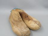 une paire de sabots en bois posés sur une surface blanche, avec un cordon bleu
