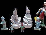 many figurines of clowns and snowmen on a black background