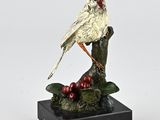 figurine of a cardinal perched on a branch with berries