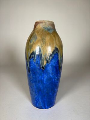 un vase bleu et or posé sur une surface blanche