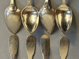 six silver spoons are lined up in a row on a table
