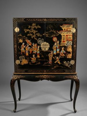 a black and gold painted cabinet on a stand