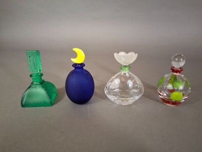 quatre vases en verre de couleurs différentes posés les uns à côté des autres sur une table