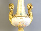 a gold vase with two cherns on it on a stand