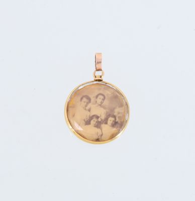 un pendentif en or avec la photo de deux femmes et d'un homme