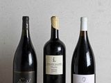 trois bouteilles de vin sont alignées sur une table en bois