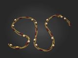 un collier en or avec des perles et une chaîne sur fond noir
