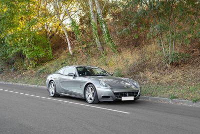 une voiture de sport argentée qui roule sur la route au milieu des bois