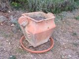 un pot en terre cuite contenant une plante, posé par terre